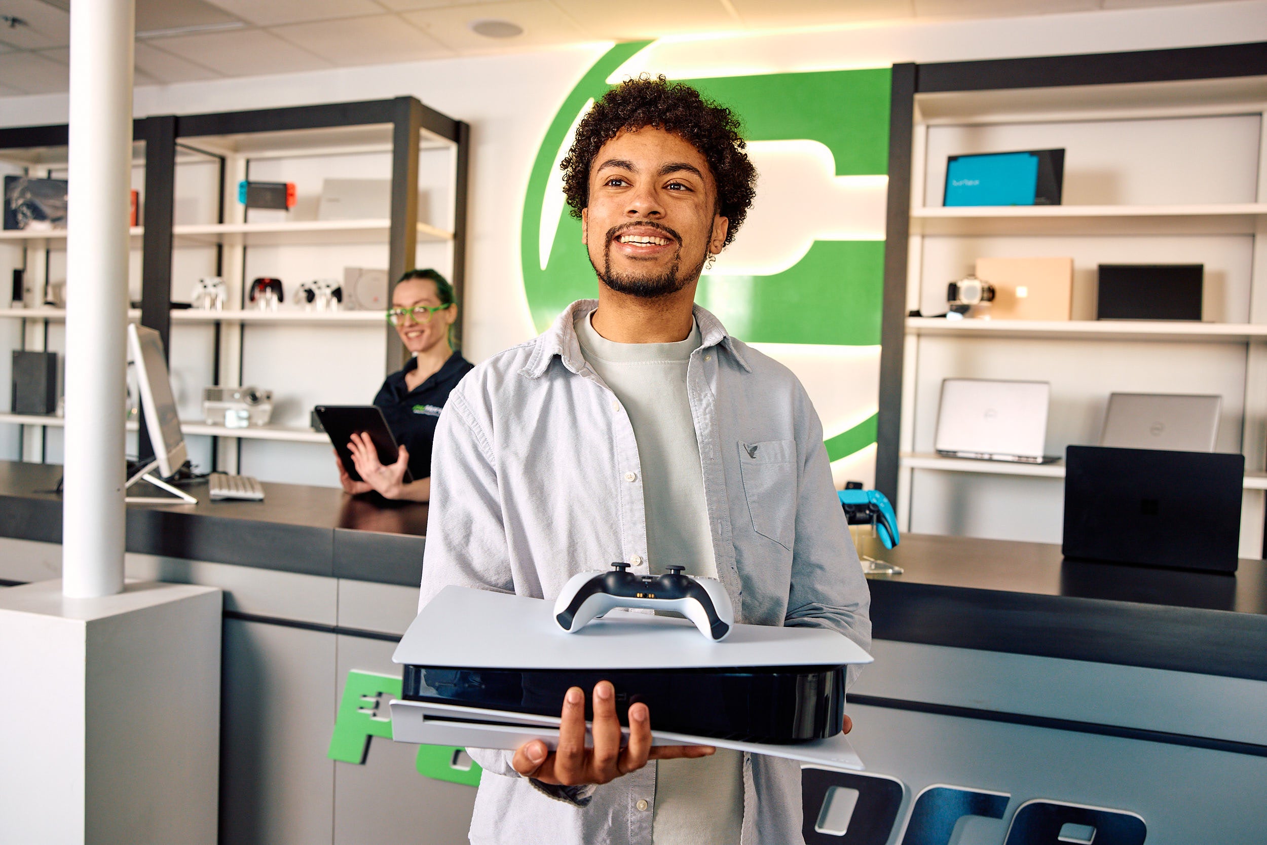 a man holding a video game system smiling in a paymore store