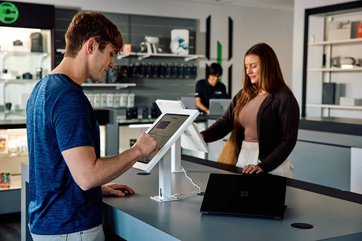 a man browsing on an ipad in a paymore store with a woman in the background