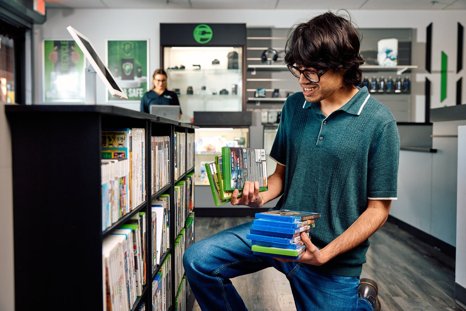 A man kneeling looking through video games in a paymore store